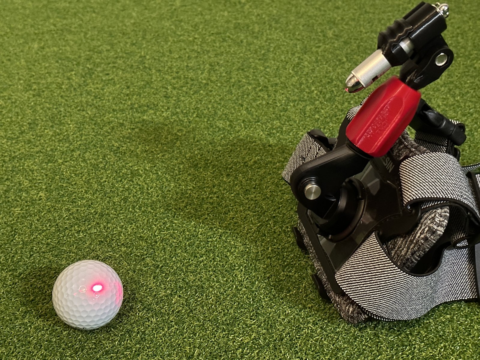 My Perfect Pivot red-dot laser aimed at a golf ball on turf